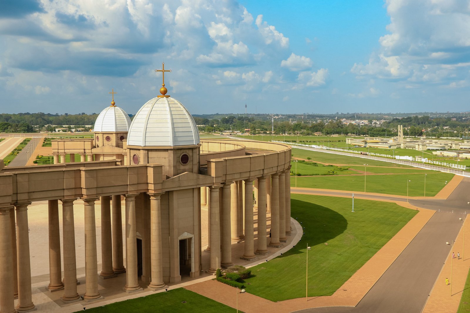 Majestic basilica stands in Yamoussoukro, showcasing unique architecture against a lush green backdrop under a blue sky.